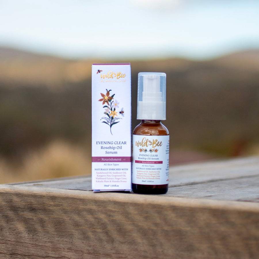 Wild Bee Evening Clear Serum on a natural product on a wooden surface with a blurred outdoor background